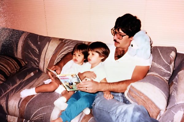 Joe Racich reading to his two young children on a couch, 1980s